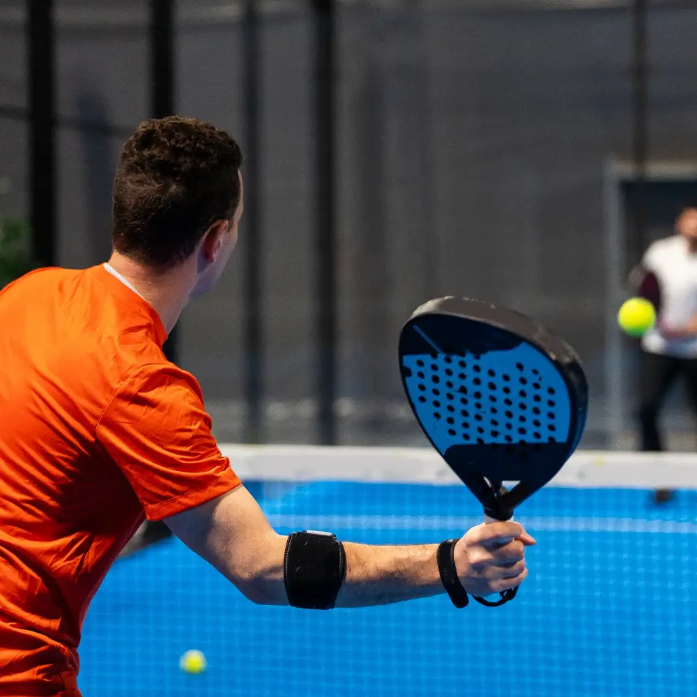 Male padel player returning the ball during an indoor match